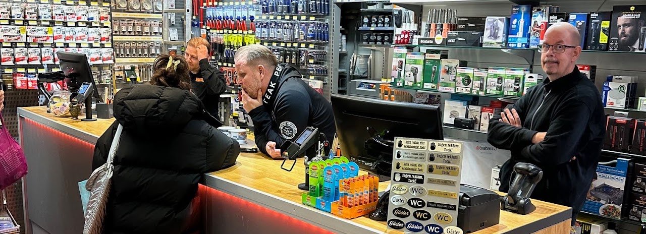 Tre anställda bakom disken i Karlaplans Järnaffär hjälper en kund i svart jacka